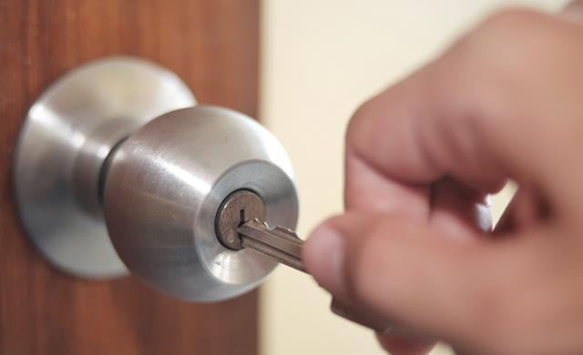 hand inserting key into door lock